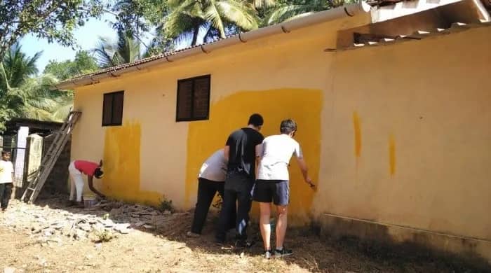 Freiwillige streichen eine Wand, Goa/Indien
