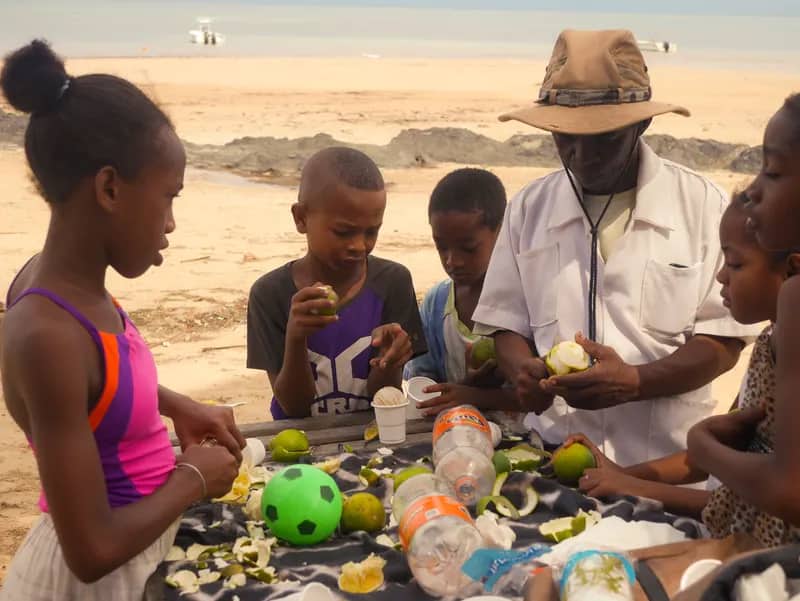 Kinder essen Obst am Strand im Kindergartenprojekt Nosy Be auf Madagaskar
